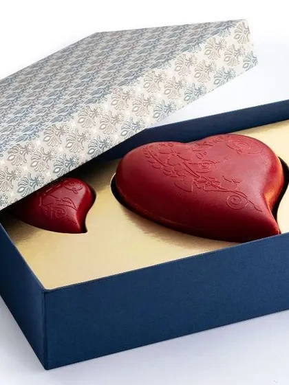 This gift box features a large red chocolate heart flanked by two smaller ones. The vibrant color is achieved using natural cocoa butter, adding a touch of romance and artistry to the gift.