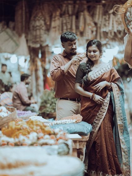 A candid moment captured in a bustling flower market, where the groom-to-be gently places a flower in his fiancée's hair, creating a truly authentic and colorful pre-wedding memory.