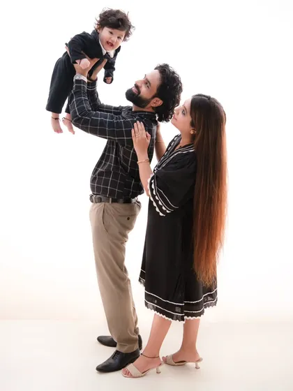 A moment of adoration. The father lifts his son, and the mother looks on with a smile, creating a dynamic and loving family portrait.