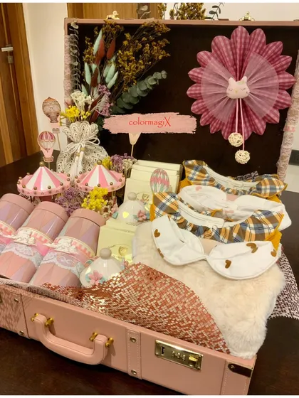 Our signature luxury trunk for a baby girl, presented in a lovely shade of pink. This hamper is filled with a curated selection of newborn giveaways, including bibs, decorative items, and keepsakes, all arranged to create a stunning visual impact.
