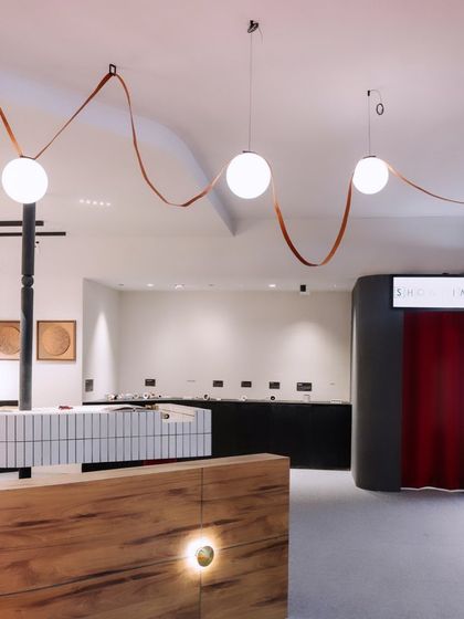 The reception area of our 'ShowTime' booth, featuring globe pendants and custom wall lighting. The design focused on creating a memorable brand experience.