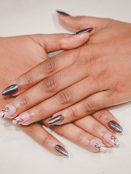 A perfect mix of edgy and sweet. We paired stunning silver chrome nails with soft pink accent nails featuring delicate, hand-painted bow details for a balanced and trendy look.