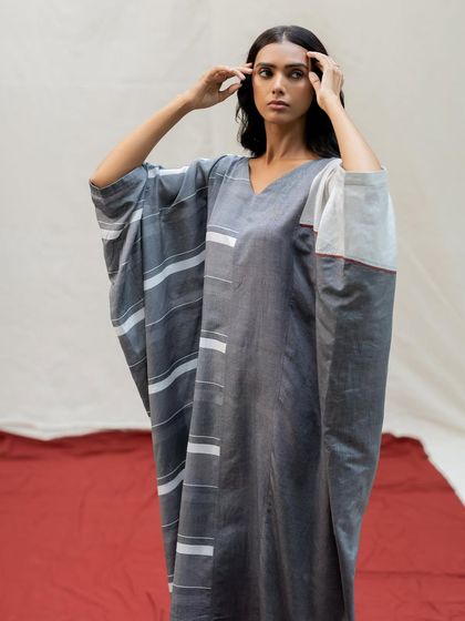 A model showcases a comfortable yet chic grey kaftan dress with modern white striped details and an easy, flowing silhouette.