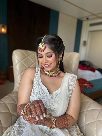 A beautiful party makeup look in a white lehenga with pink accents. The smokey eye and braided ponytail create a style that is both trendy and timeless.