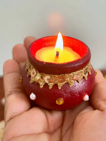 A close-up of our hand-painted matki candle. The small details and earthy feel make it a unique addition to your festive decor.