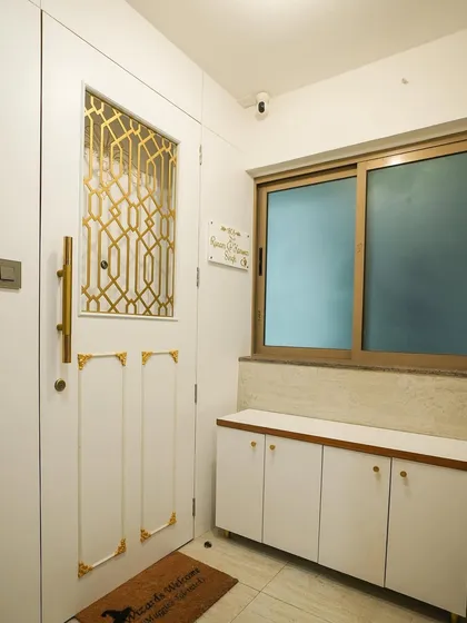 The transformation is complete with a new white and gold safety door, a custom nameplate, and a sleek shoe cabinet, creating a bright and welcoming entryway.