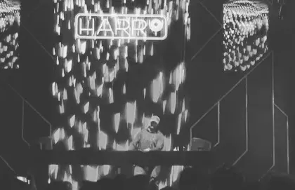 A solo shot on stage with my name and visuals behind me. This black and white photo captures the focus of a closing set.