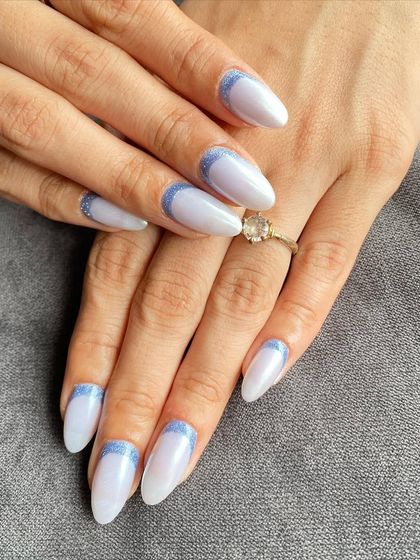 A full view of the pearlescent white nails with a glittery blue reverse French design. So dreamy.