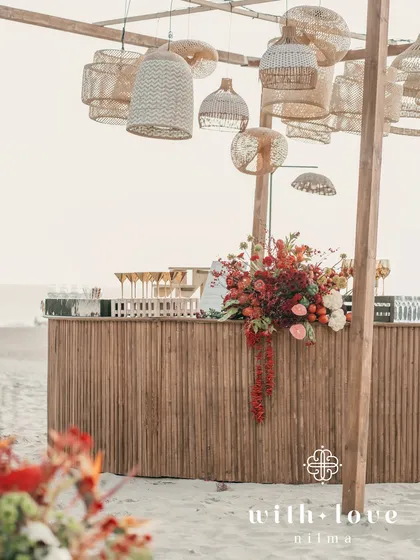 The bar area at the beach event, with rattan lamps and a beautiful view of the ocean.