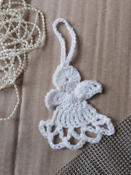 A delicate crochet angel ornament, perfect for hanging on your Christmas tree or as a special gift topper.