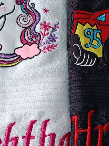 A close-up of the detailed embroidery on the unicorn and 'Cars' themed towels.