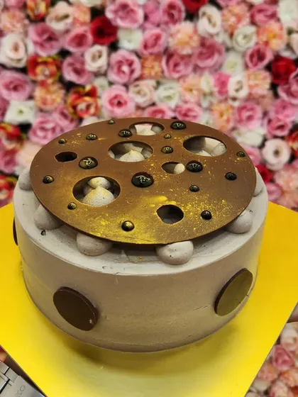 A celebration cake made with butterscotch, choco-chips, and lots of love. This unique design features a golden chocolate disc with holes, giving a peek at the creamy topping underneath.
