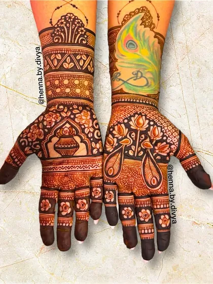 A unique design featuring a pop of color with a painted peacock feather on one arm. The palms are adorned with a kalash and other traditional Indian motifs.