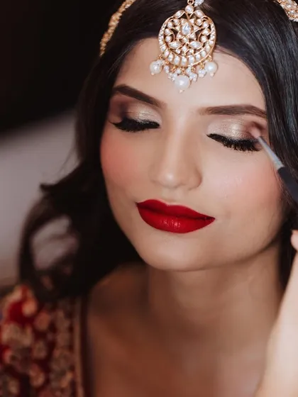 A close-up of the makeup application. This shot highlights the precision and artistry involved in creating the perfect bold red lip and shimmering eye.