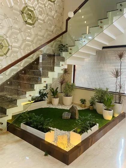 This project showcases our ability to create serene green spaces in unconventional areas. We transformed the space under a staircase in a Faridabad residence into a miniature courtyard garden, using a combination of artificial turf, white pebbles, potted plants, and integrated uplighting.