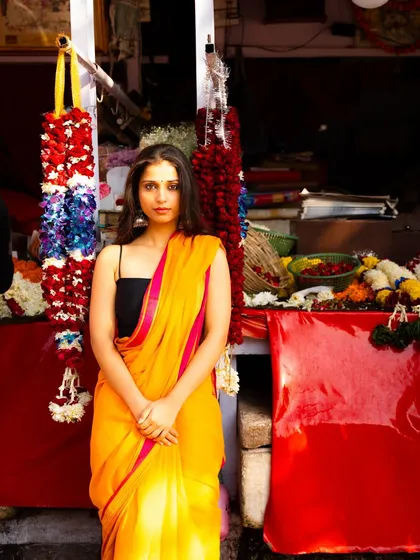 Using a local flower stall as a backdrop. The vibrant red of the stall and the flowers complement the model's bright saree perfectly.