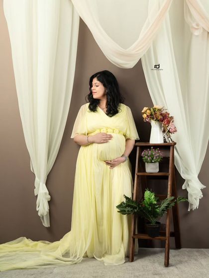 A graceful solo portrait in a flowing yellow gown. The soft drapes and floral props add a touch of romance and elegance to the scene.