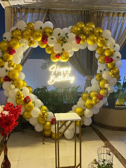 An impressive heart-shaped balloon arch made of gold and white balloons, accented with red roses. This arch creates a perfect photo backdrop for birthdays, anniversaries, or proposals.
