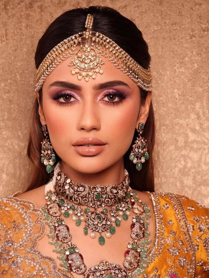 A close-up of a bride in a yellow lehenga, featuring a dramatic purple smokey eye. This shows my ability to play with colour in a sophisticated way for bridal looks.