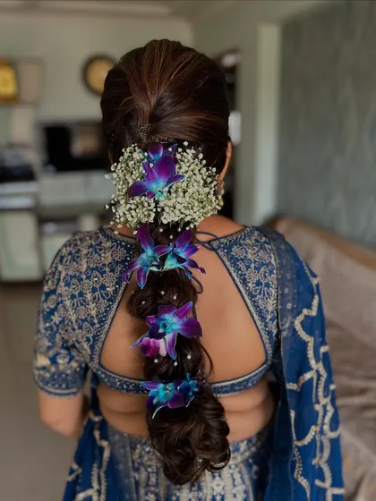 A stunning traditional hairstyle featuring a thick braid adorned with fresh baby's breath and vibrant purple orchids. This is a classic choice for South Indian weddings and ceremonies.