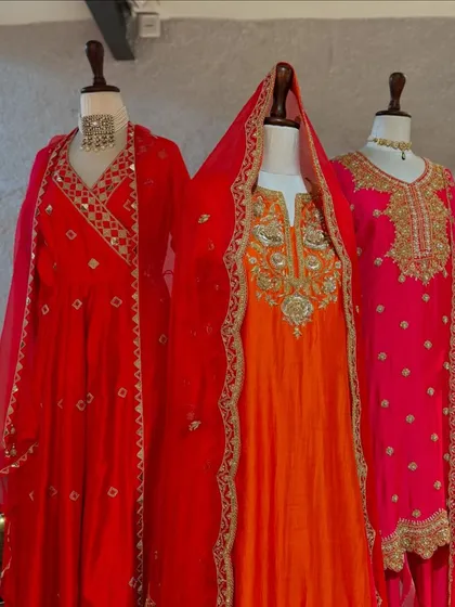 The full trio of red, orange, and pink suits, each offering a different level of ornamentation but all sharing a celebratory spirit.