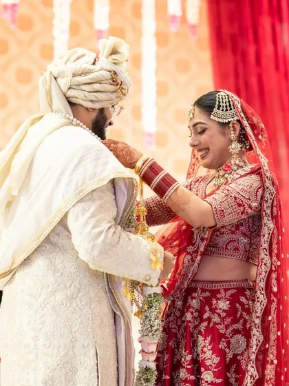 A close up of the varmala exchange, focusing on the couple's interaction and the beautiful floral garlands.