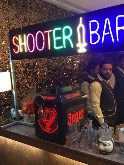 My team is ready to serve at the shooter bar. This setup against a gold sequin wall includes a Jägermeister machine, ensuring the shots are perfectly chilled.
