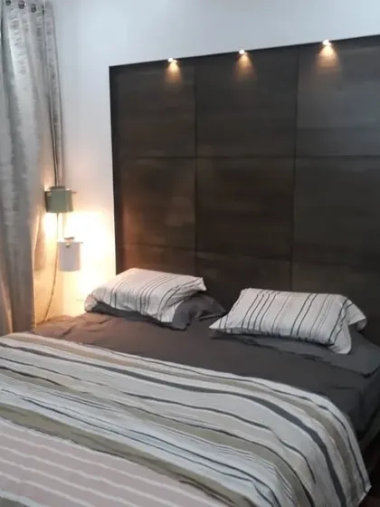 Our expertise in custom woodwork is highlighted in this elegant bedroom headboard. We crafted this dark wood paneled feature wall with integrated spotlights, creating a sophisticated focal point that provides perfect lighting for evening reading and adds a layer of architectural depth to the room.