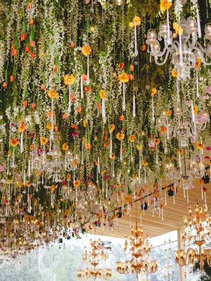 The ceiling of the reception tent was a work of art, featuring a dense installation of hanging greenery, colorful tulips, and candles, creating a magical floating garden above the guests.