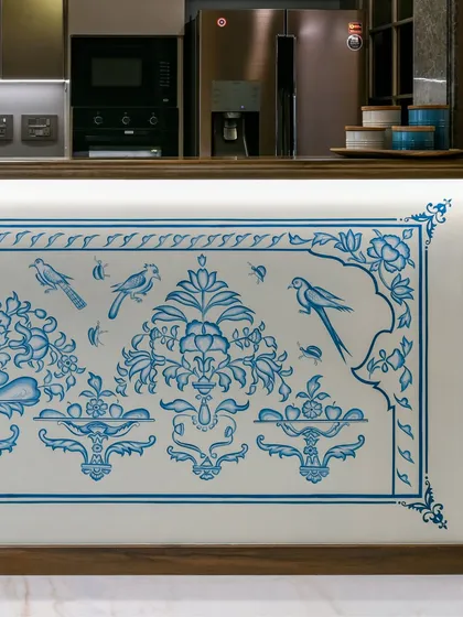 A detail of the hand-painted kitchen counter mural, showing the delicate birds and floral patterns. This close-up reveals the precision and artistry of the craftsmen, whose work brings a personal and rooted story to the heart of the home.