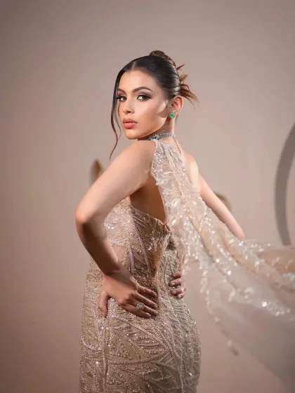 A back view of the champagne gown, showcasing its elegant drape and flowing cape. This look is all about creating a sense of drama and movement.