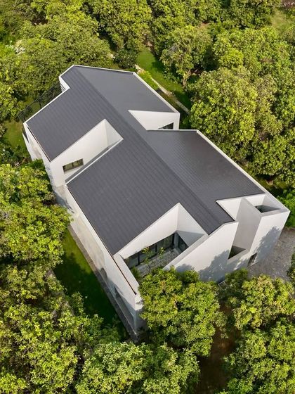 This image shows the full extent of the Mango Orchard House, a 13,000 sq.ft. weekend home conceived as a tranquil retreat that fosters a deep connection with the surrounding landscape.