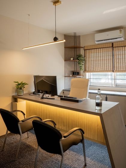 A private cabin designed for focus and clarity. The desk features an under-lit fluted panel, and natural light is controlled with bamboo blinds, creating a calm and productive atmosphere.