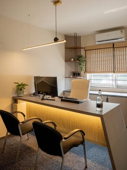 A private cabin designed for focused work, featuring a sleek, modern desk with integrated lighting. Natural textures like the bamboo blinds and a touch of greenery create a calm and productive atmosphere.