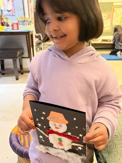 A happy student shows off her adorable snowman craft. I love seeing their personalities shine through in the little details they add, like the snowman's hat and scarf.