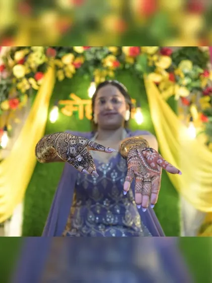 A classic mehendi pose where the bride proudly displays her intricate henna designs. I make sure to get these detailed shots, highlighting the artistry of the mehendi against the festive backdrop.