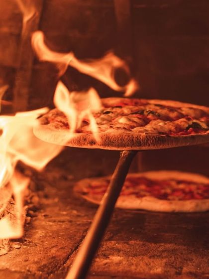 The glow of the wood fire is a vibe you can't resist. This is the view from our Palace Road location, showing the same authentic ovens we can bring to your event.