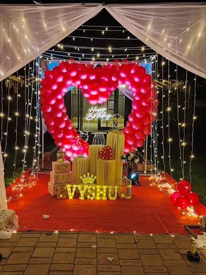 We specialize in creating unforgettable romantic surprises. This stunning outdoor cabana setup features a heart-shaped balloon arch, a red carpet entrance, and magical fairy lights, perfect for a birthday or anniversary celebration.