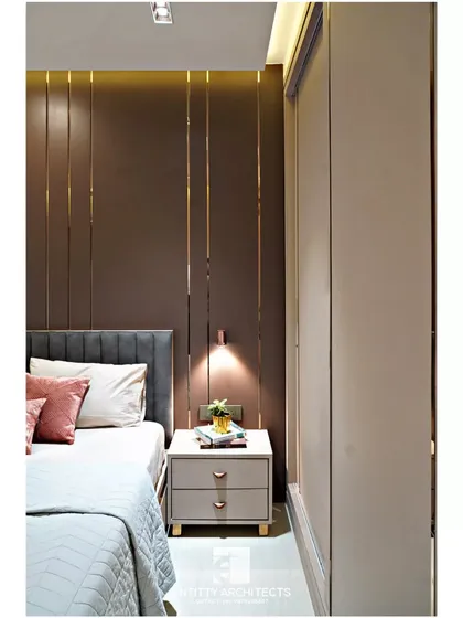 A closer look at the custom headboard wall in the Pote Residence. The vertical panels are accented with thin rose gold metal strips and complemented by a sleek, custom-designed bedside table.