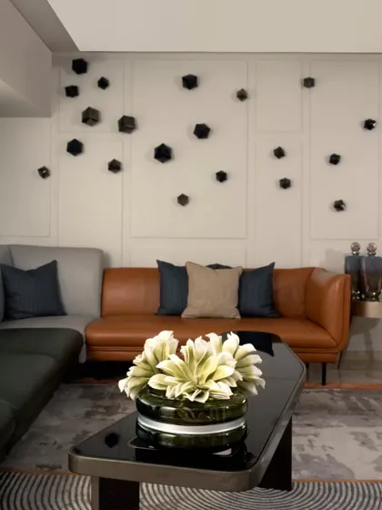 This shot highlights the use of layered textures and statement art. The custom wall cubes from White Domus add a sculptural element, while the tan leather sofa brings warmth to the monochrome color scheme.