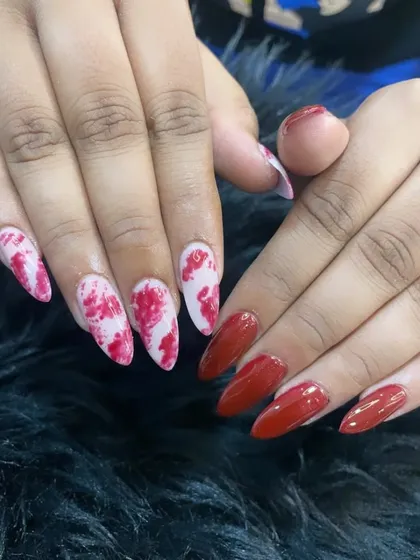 A dramatic set combining solid glossy red nails with red and white marble-effect accent nails on a stiletto shape.