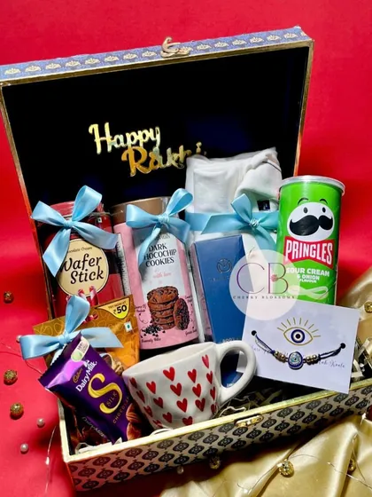 Another view of our luxurious Rakshabandhan hamper. The elegant peacock-themed box is filled with a variety of treats, a shirt, a mug, and an evil eye rakhi to complete the gift.