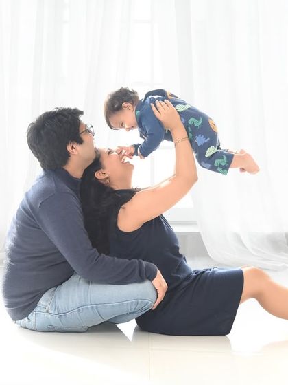 A moment of pure joy as a mother lifts her baby high in the air. This playful interaction, captured in our bright white studio, results in a beautiful, candid family photograph.