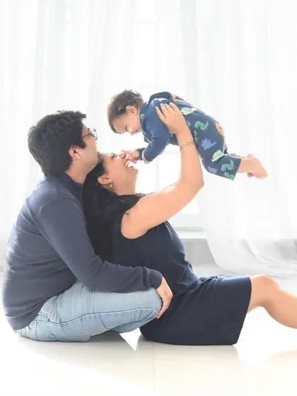 A moment of pure joy as a mother lifts her baby high in the air. This playful interaction, captured in our bright white studio, results in a beautiful, candid family photograph.
