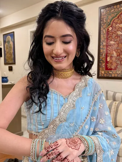 The bride admiring her simple, elegant henna. The soft makeup look ensures that all the details of her Roka ceremony come together beautifully.