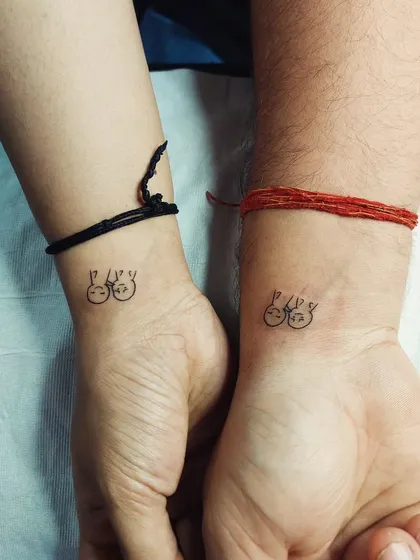 A cute matching tattoo for a couple, showing two simple, happy faces. It’s a playful and minimalist way to celebrate a connection.