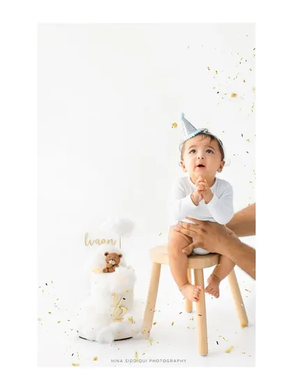 "Just a little taste?" This shot perfectly captures the anticipation and curiosity of a baby seeing his half birthday cake for the first time. The little party hat adds a festive touch.