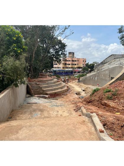 A construction site photo of the "Indoor Sports Center," showing the earthworks and concrete forms that will become landscaped plazas and amphitheaters.