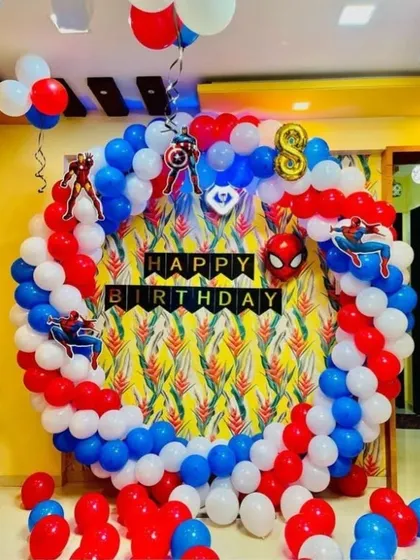 An action-packed superhero birthday party. This circular balloon arrangement in red, white, and blue is decorated with cutouts of Spider-Man, Iron Man, and Captain America's shield.