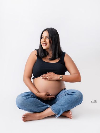 A happy, relaxed portrait of a mom-to-be sitting cross-legged in the studio.